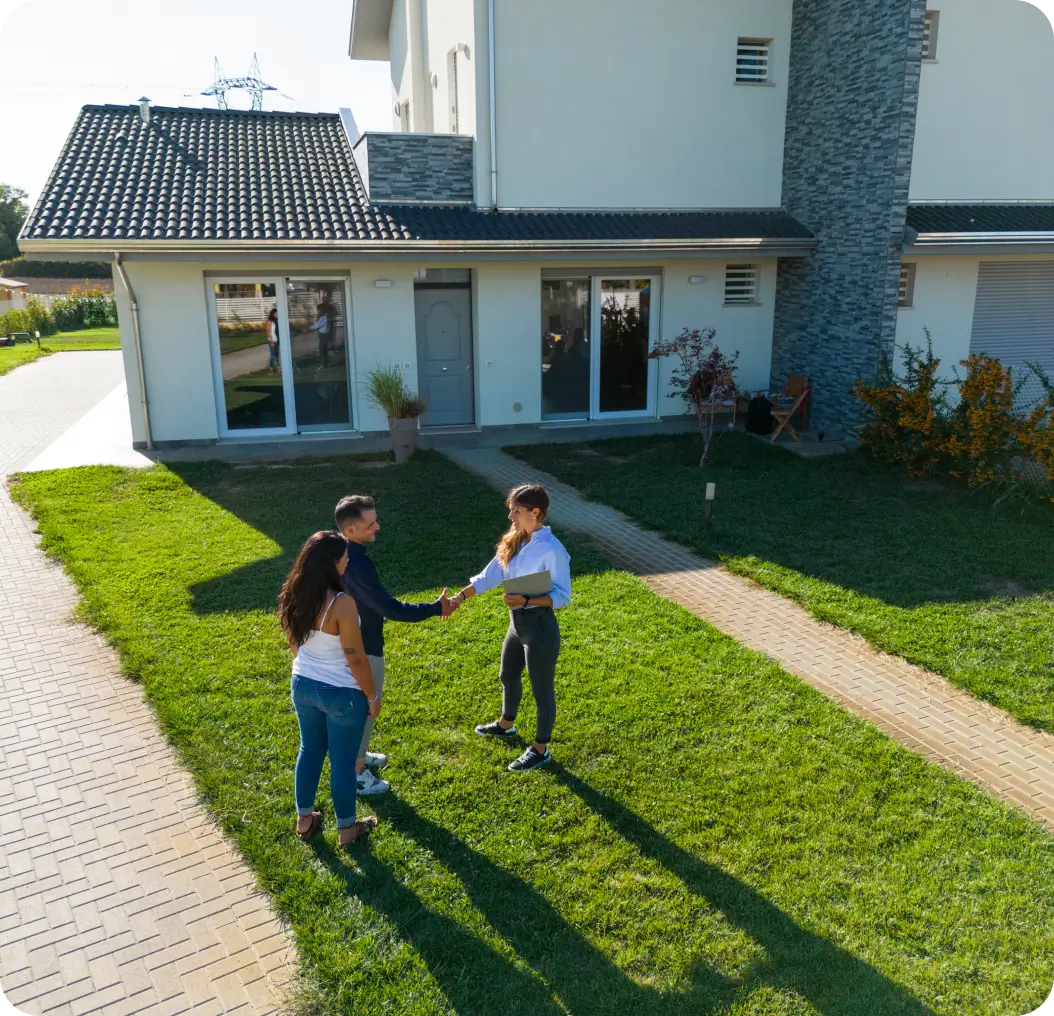 People shaking hands outside a modern house.