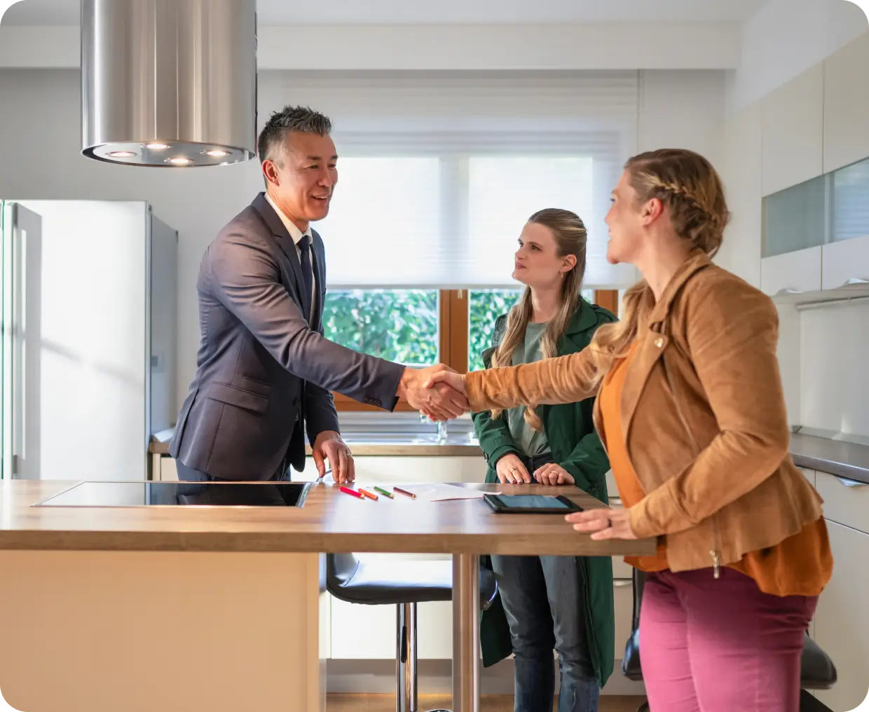 Real estate agreement handshake in modern kitchen.